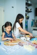 © tuastockphoto - Asian girl in casual dress having fun while make pizza with prosciutto, tomato, cheese, vegetables in home kitchen. family and relationship concept