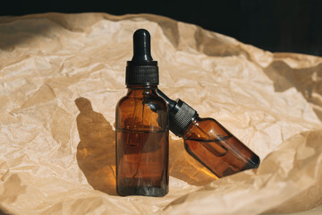 Mock-up of a set of empty cosmetic containers with pipettes made of amber glass on a beige background with crumpled paper like wrinkles. Concept of natural skin care, spa.