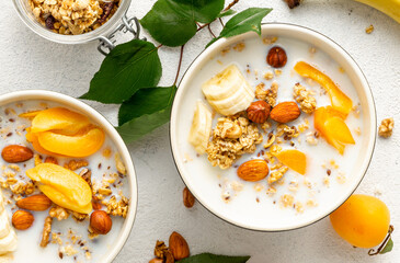 Wall Mural - Granola cereal with fruits, nuts and milk in bowl on a white background. Healthy breakfast cereal top view