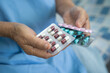 © amazing studio - Asian senior or elderly old lady woman patient holding antibiotics capsule pills in blister packaging for treatment infection patient in hospital, Pharmacy drugstore concept.