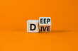 Deep dive symbol. Turned a wooden cube with words 'Deep dive'. Beautiful orange table, orange background. Deep dive and business concept. Copy space.