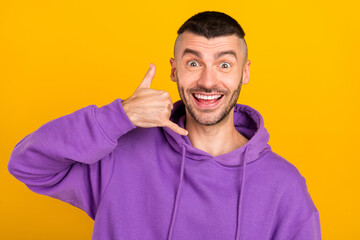 Poster - Photo of funny young brunet guy call me wear violet hoodie isolated on yellow color background