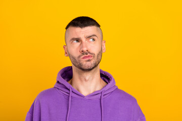 Poster - Photo of serious millennial brunet guy look empty space wear violet hoodie isolated on yellow color background