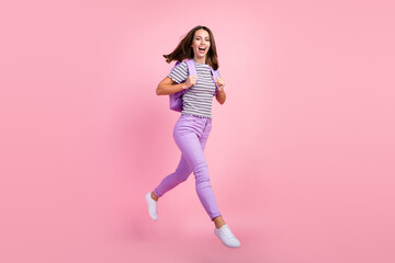 Wall Mural - Photo of funky charming young lady wear striped outfit backpack smiling jumping high walking isolated pink color background