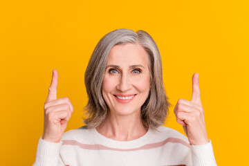 Sticker - Photo of pretty adorable lady pensioner wear striped pullover pointing up empty space smiling isolated yellow color background