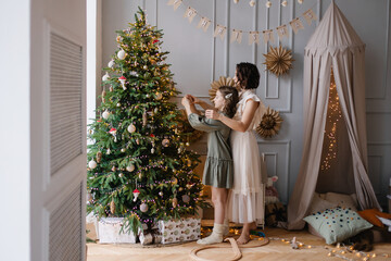 Wall Mural - Mother and daughter decorate the Christmas tree together. Stylish interior of a children's room. Scandinavian eco-style decor. New Year celebration. Christmas eve. Support joint time forwarding. love