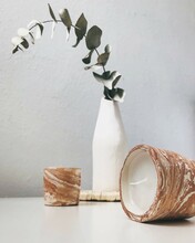Two Candles Next To A Eucalyptus Branch In A Vase