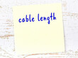 Yellow sticky note on wooden wall with handwritten word cable length