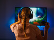 © Anton - Blonde girl gamer is playing a video game. She has headphones on her head, a joystick in her hand. Large monitor. Neon light. Concept - video games, gambling business, leisure, hobbies.