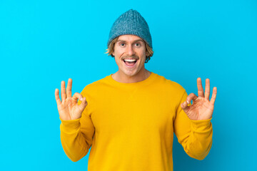 Handsome blonde man isolated on blue background showing ok sign with two hands