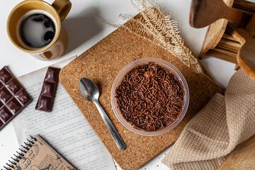 Carrot and chocolate jar cake vintage composition with cork, notebook, book page, coffee mug, kitchen cloth, chocolate bar and wooden kitchen utensils. Food concept.