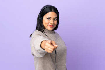 Wall Mural - Young latin woman woman isolated on purple background listening music and pointing to the front