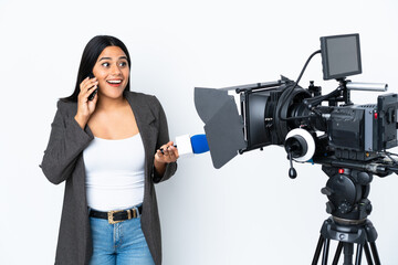 Wall Mural - Reporter Colombian woman holding a microphone and reporting news on white background keeping a conversation with the mobile phone with someone