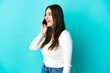 © luismolinero - Young caucasian woman isolated on blue background keeping a conversation with the mobile phone