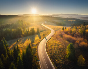 Wall Mural - aerial view of mountain road in forest at sunset in autumn. top view from drone of road in woods. be