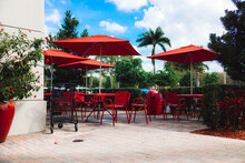 Outdoor Cafe With Red Tables, Chairs And Umbrella