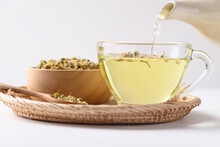 Chamomile Tea In A Teapot Pouring Into Cup Glass With Dried Chamomile Flowers In A Bowl On White Background, Healthy Herbal Tea