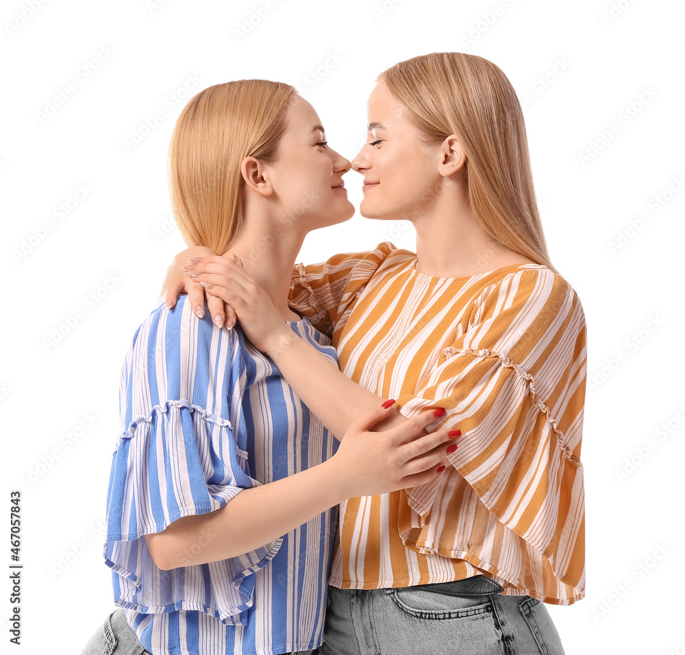 Beautiful young twin sisters hugging on white background