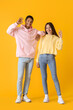 © Pixel-Shot - Stylish young couple in hoodies showing OK on yellow background