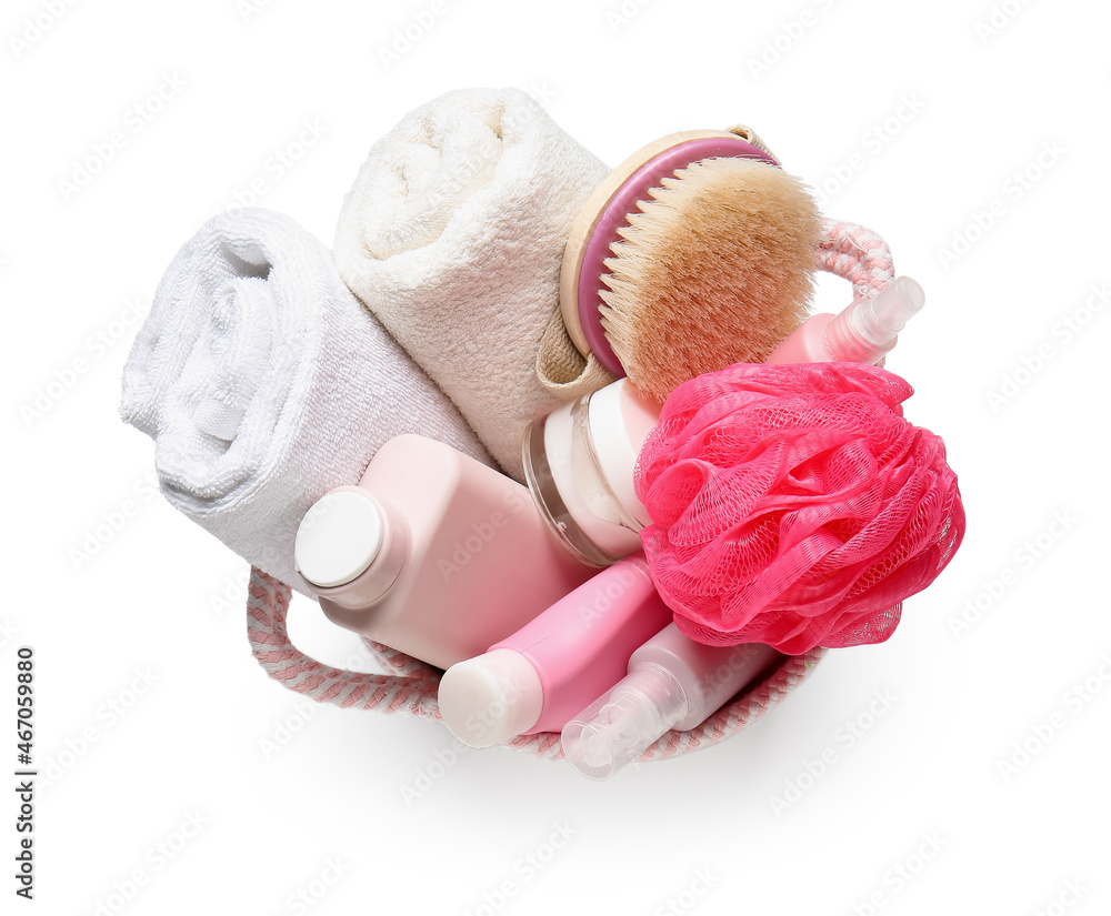 Basket with bath supplies, sponge and towels on white background