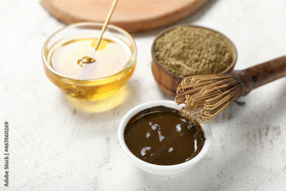 Bowl with hojicha powder, honey and chasen on light background