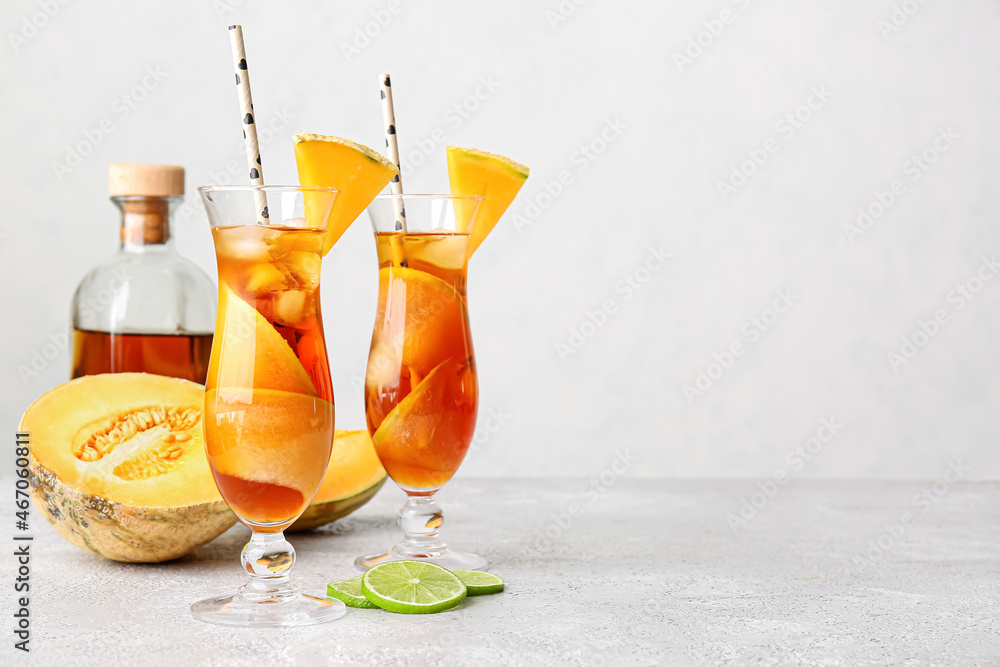 Glasses with delicious cocktail and melon on light background