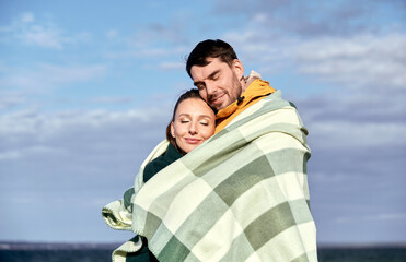 Poster - love, relationship and people concept - happy smiling couple in warm blanket on autumn beach