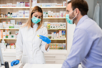 Wall Mural - Male customer with protective mask on his face buying pills in modern drugstore.