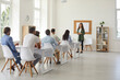 © Studio Romantic - Adult education. Team of employees sit at tables in a bright auditorium and listen to a business specialist. Female coach talks about the business development strategy during the business meeting.