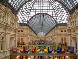 Moscow, Russia - October 5, 2021: GUM is the main department store. On the top floor, under the dome of the roof, there are cafes with brightly colored sofas.