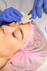 Wall Mural - Young caucasian woman having ultrasonic peeling with ultrasound device in a cosmetic beauty salon