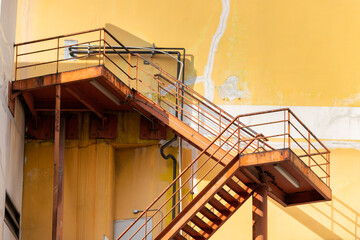 Wall Mural - outdoor fire exit stair of old yellow building. rusty fire escape metal stair.