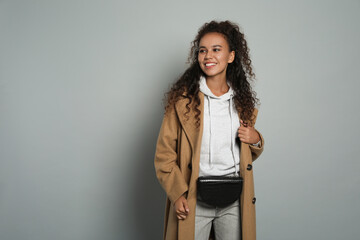 Canvas Print - Beautiful African American woman with stylish waist bag on grey background, space for text