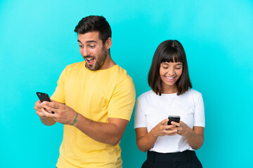 Poster - Young couple isolated on blue background sending a message or email with the mobile