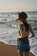 © VICHIZH - cheerful woman in sunglasses and a hat walks along the ocean