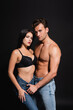 © LIGHTFIELD STUDIOS - sexy young couple in jeans looking at camera while standing isolated on black