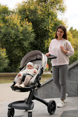 Canvas Print - Young mother walking with her adorable baby in stroller outdoors