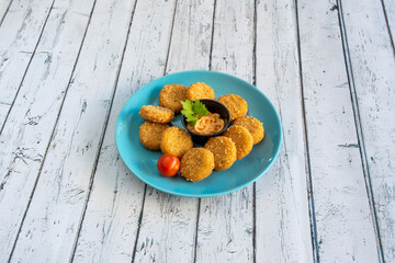 Wall Mural - Portion of chicken nuggets battered in flour and egg with cheese sauce to dip on a blue plate