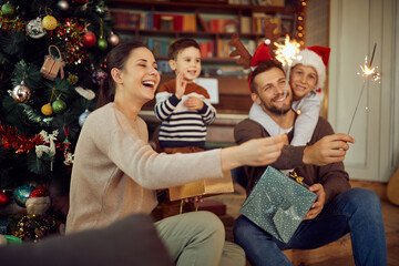 Wall Mural - Happy family has fun with sparkles while celebrating Christmas at home.