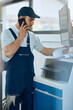 © Drazen - Car mechanic talks on the phone while going through paperwork at repair shop.