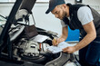 © Drazen - Auto mechanic writes data during engine maintenance at car service workshop.