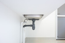Drain pipe or sewer under kitchen sink. Pvc plastic pipe and
 flexible supply tube connection to stainless steel sink include faucet, trap for drain water and waste in drainage and plumbing system.