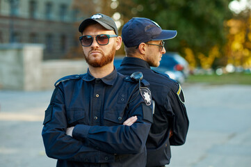 Wall Mural - Two male police officers standing back to back