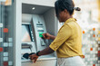 © Zamrznuti tonovi - African american woman using an atm machine and a credit card