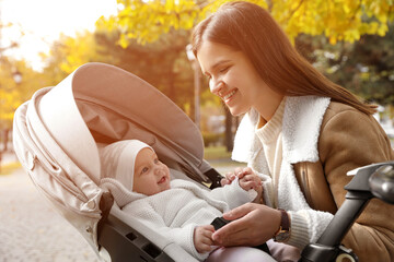 Canvas Print - Happy mother with her baby daughter in stroller outdoors on autumn day