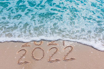 Wall Mural - message year 2021 replaced by 2022 written on beach sand background. good bye 2021 hello to 2022 hap