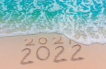 Wall Mural - message year 2021 replaced by 2022 written on beach sand background. good bye 2021 hello to 2022 hap