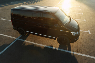 Wall Mural - Black van on parking lot at sunset outdoors