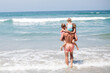 © Scopio - Backside of man standing on seashore holding three children