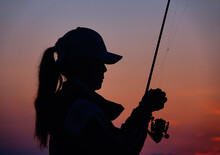 Silhouette Of Woman Holding Fishing Rod